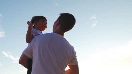 Happy little boy runs into arms of father, father kneels on the sand near tent father holding his son in the air, father holding son on sandy beach, happy family carefree childhood concept.の写真素材