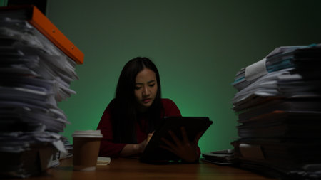 Stressed young asian woman sitting work overtime doing late time business at office in night on desk, Exhausted businesswoman concept.の写真素材