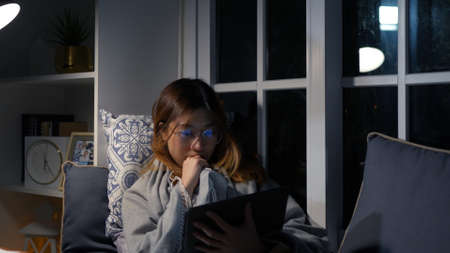 Asian businesswoman or freelancer working hard at the night looking the laptop digital tablet and document in workplace at late overtime deadline, Stressed busy and exhausted of work at home.の写真素材