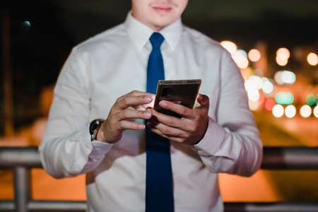 Asian businessman use wireless earbuds listening music in the modern city at nightの写真素材