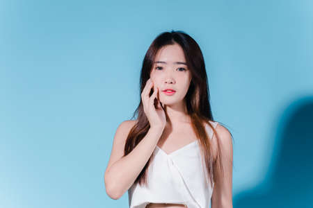Charming asian beauty woman hold sun cream with sun protection uv or sunscreen on the blue backgroundの写真素材
