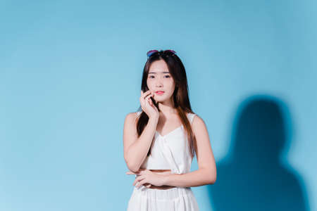 Charming asian beauty woman hold sun cream with sun protection uv or sunscreen on the blue backgroundの写真素材