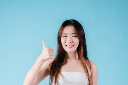 Charming portrait of Asian woman smiling confidence beauty make up on the blue backgroundの写真素材