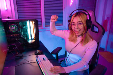 Gamer female playing virtual reality games cyber sport and esport. Young woman getting 3D experience with VR in room colorful neon lights.の写真素材