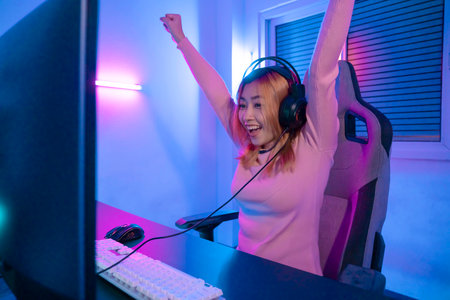 Gamer female playing virtual reality games cyber sport and esport. Young woman getting 3D experience with VR in room colorful neon lights.の写真素材