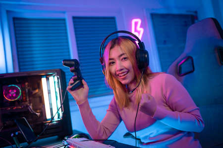 Gamer female playing virtual reality games cyber sport and esport. Young woman getting 3D experience with VR in room colorful neon lights.の写真素材