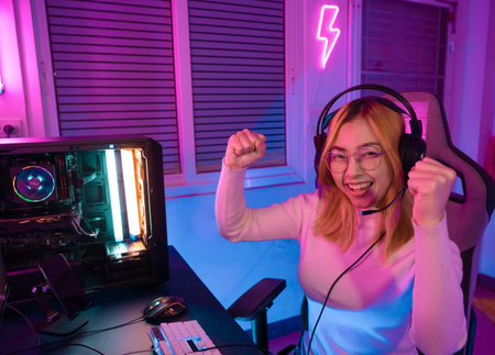 Gamer female playing virtual reality games cyber sport and esport. Young woman getting 3D experience with VR in room colorful neon lights.の写真素材