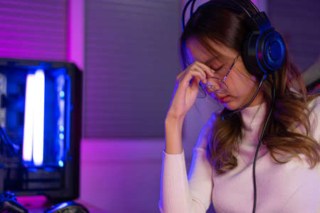 Eyes tired. Gamer and E-Sport online of Asian woman playing online computer video game with lighting...