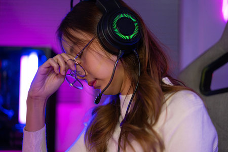 Eyes tired. Gamer and E-Sport online of Asian woman playing online computer video game with lighting...