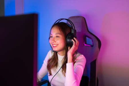 Young people Backache. Gamer and E-Sport online of Asian woman playing online computer video game with lighting effect,の写真素材