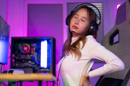 Young people Backache. Gamer and E-Sport online of Asian woman playing online computer video game...