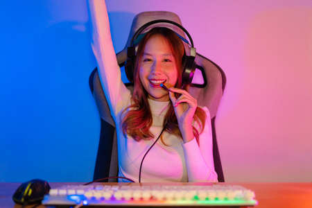 Asian gamer playing online video game winning excited on PC with lighting effect, broadcast streaming live at home. Gamer and E-Sport online gaming technology Championship tournament gamer concept.の写真素材