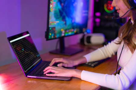 Woman playing online video game and trading on price chart digital stock exchange. broadcast streaming live at home. Gamer and E-Sport online gaming technology Championship tournament gamer concept.の写真素材