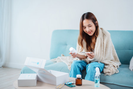 Asian young woman patient on eating table at nursing home care. Female look to medicine pills in bottle, read prescription and content. self recover health care concept.の写真素材
