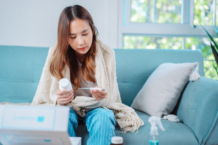 Asian young woman patient on eating table at nursing home care. Female look to medicine pills in bottle, read prescription and content. self recover health care concept.の写真素材