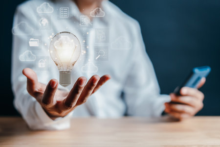 Hand holding virtual lightbulb with cloud computing and technology icon. businessman using smart phone. Cloud management big data include business strategy, backup and upload data in network.の写真素材