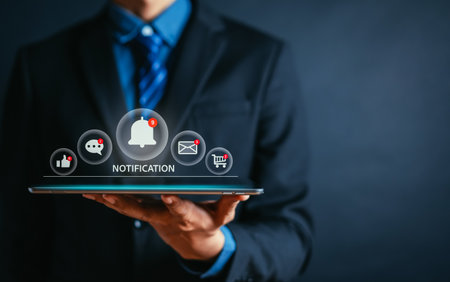 Businessman holding tablet with virtual bell ringing for application notification alert interface...
