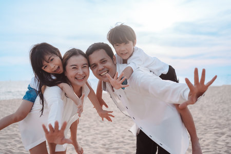 Happy asian family enjoy the sea beach at consisting father, mother,son and daughter having fun playing beach in summer vacation on the ocean beach. Happy family with vacations time lifestyle concept.の写真素材