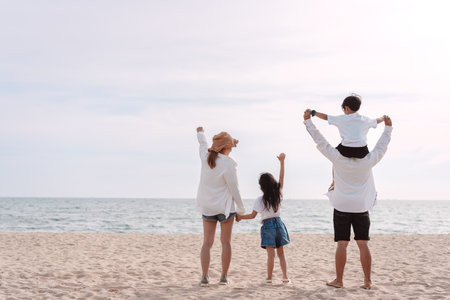 Happy asian family on the beach in holiday. of the family holding hands, Son and daughter piggyback...