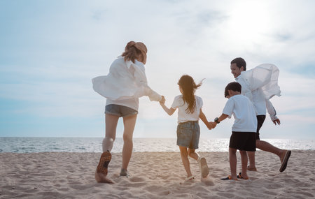 Happy asian family enjoy the sea beach at consisting father, mother,son and daughter having fun playing beach in summer vacation on the ocean beach. Happy family with vacations time lifestyle concept.の写真素材