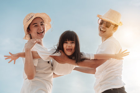 Happy asian family enjoy the sea beach at consisting father, mother and daughter having fun playing beach in summer vacation on the ocean beach. Happy family with vacations time lifestyle concept.の写真素材