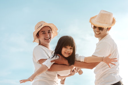 Happy asian family enjoy the sea beach at consisting father, mother and daughter having fun playing beach in summer vacation on the ocean beach. Happy family with vacations time lifestyle concept.の写真素材