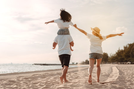 Happy asian family enjoy the sea beach at consisting father, mother and daughter having fun playing beach in summer vacation on the ocean beach. Happy family with vacations time lifestyle concept.の写真素材