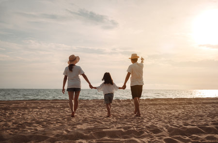 Happy asian family enjoy the sea beach at consisting father, mother and daughter having fun playing beach in summer vacation on the ocean beach. Happy family with vacations time lifestyle concept.の写真素材