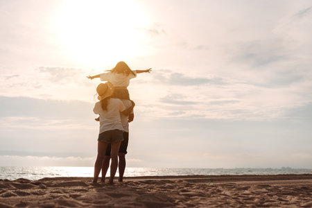 Happy asian family enjoy the sea beach at consisting father, mother and daughter having fun playing beach in summer vacation on the ocean beach. Happy family with vacations time lifestyle concept.の写真素材