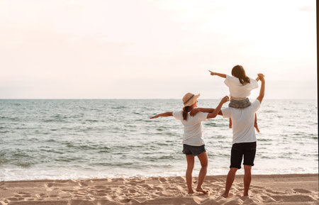 Happy asian family enjoy the sea beach at consisting father, mother and daughter having fun playing beach in summer vacation on the ocean beach. Happy family with vacations time lifestyle concept.の写真素材