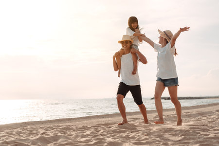 Happy asian family enjoy the sea beach at consisting father, mother and daughter having fun playing beach in summer vacation on the ocean beach. Happy family with vacations time lifestyle concept.の写真素材
