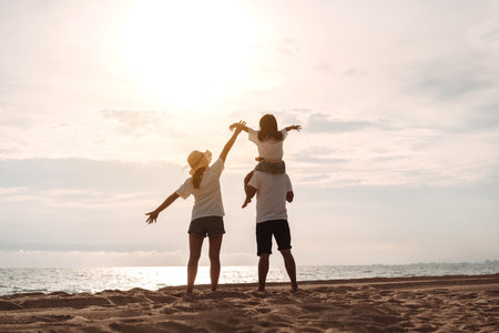 Happy asian family enjoy the sea beach at consisting father, mother and daughter having fun playing beach in summer vacation on the ocean beach. Happy family with vacations time lifestyle concept.の写真素材