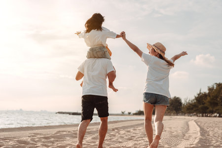 Happy asian family enjoy the sea beach at consisting father, mother and daughter having fun playing beach in summer vacation on the ocean beach. Happy family with vacations time lifestyle concept.の写真素材