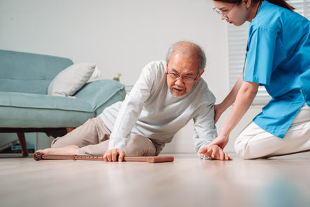 Asian caregiver helping senior male from falling on the ground. Older elderly man patient having accident heart attack when physical therapy. Nurse assistance rescue concept.の写真素材