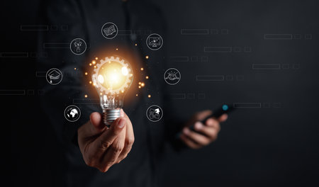 Man hand holding lightbulb with learning educate and graduation concept. study knowledge to creative thinking idea and problem solving solution, E-learning online education course degree certificateの写真素材