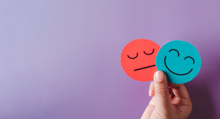 Hands holding sad face hiding or behind happy smiley face, bipolar and depression, mental health...
