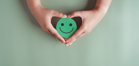 Hands holding green happy smile face, good feedback rating, positive customer review, experience,...