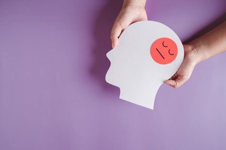 hands holding sad or angry face in brain paper cut, feeling mood unhappy hormones, imbalance brain chemicals, negative mental health care conceptの写真素材
