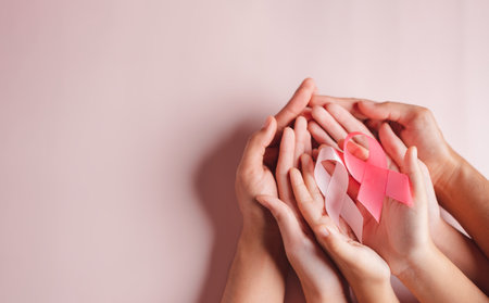 hands of people holding pink ribbons on pink background, Breast cancer awareness, world cancer day, national cancer survivor day in february concept.の写真素材