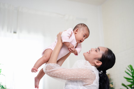 Mother Parenting and newborn birth life. Mom and baby boy playing in sunny bedroom, Family having...