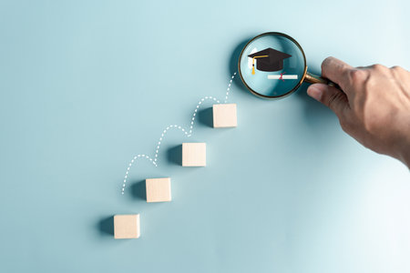Steps of education leading to success goal. Taking strategic steps towards graduation. Career path and first for business, Graduation achievement goals concept. Graduation cap on wooden block.の写真素材