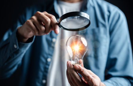 Businessman focus with magnifying to light bulb with business target planning idea and creativity innovation development leadership investment growth and success development, goal, strategyの写真素材