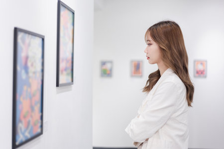 Woman visiting art gallery her looking pictures on wall watching photo frame painting at artwork museum people lifestyle concept.の写真素材