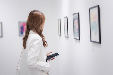 Woman visiting art gallery her looking pictures on wall watching photo frame painting at artwork museum people lifestyle concept.の写真素材