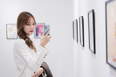 Woman visiting art gallery her looking pictures on wall watching photo frame painting at artwork museum people lifestyle concept.の写真素材