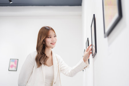 Woman visiting art gallery her looking pictures on wall watching photo frame painting at artwork museum people lifestyle concept.の写真素材