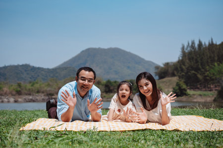 Happy family in the nature travel. family on weekend playing together in the meadow with river Parents hold the child and daughter hands.health life insurance plan concept.の写真素材