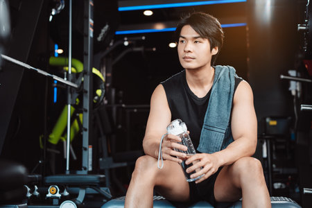 Man exercise workout in gym fitness breaking and resting after training sport with dumbbells and water bottle healthy lifestyle bodybuilding.の写真素材