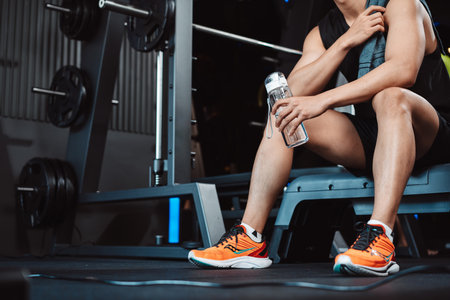 Man exercise workout in gym fitness breaking and resting after training sport with dumbbells and water bottle healthy lifestyle bodybuilding.の写真素材