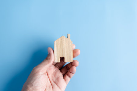 Hand holding wooden house, family home, homeless housing, mortgage crisis and home protection insurance, international day of families, foster home care, family day care, stay home conceptの写真素材